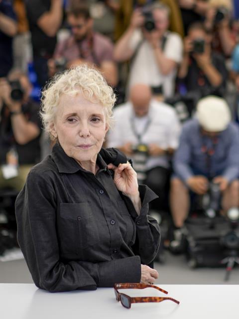 Claire Denis on a red carpet in a black collared shirt