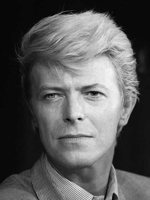 A black and white image of David Bowie with swept back hair