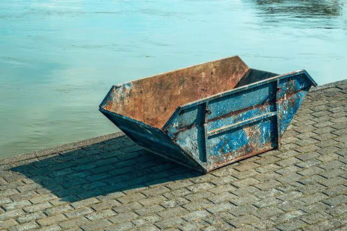 Old worn skip container on riverbank
